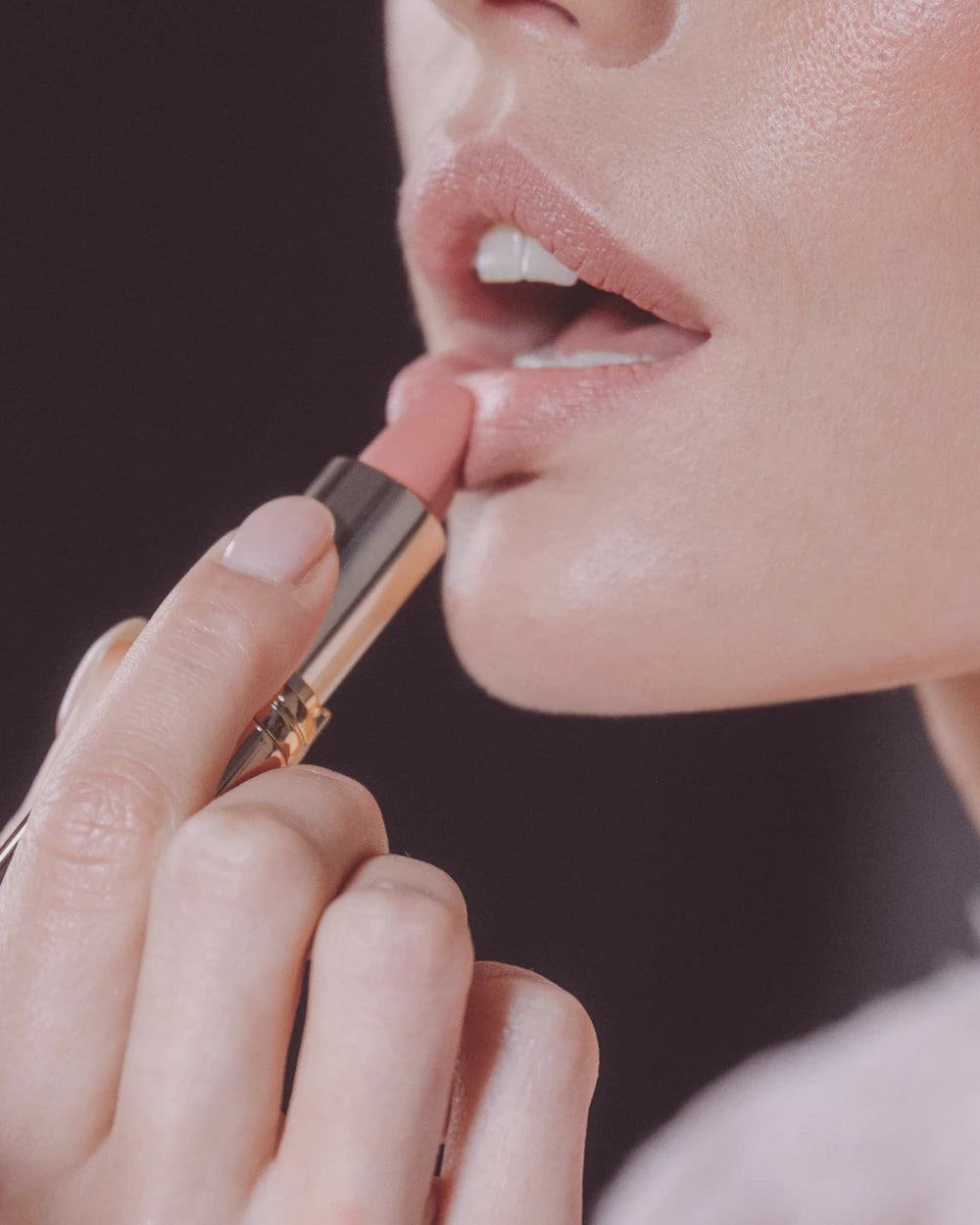 Woman applying a nude lipstick