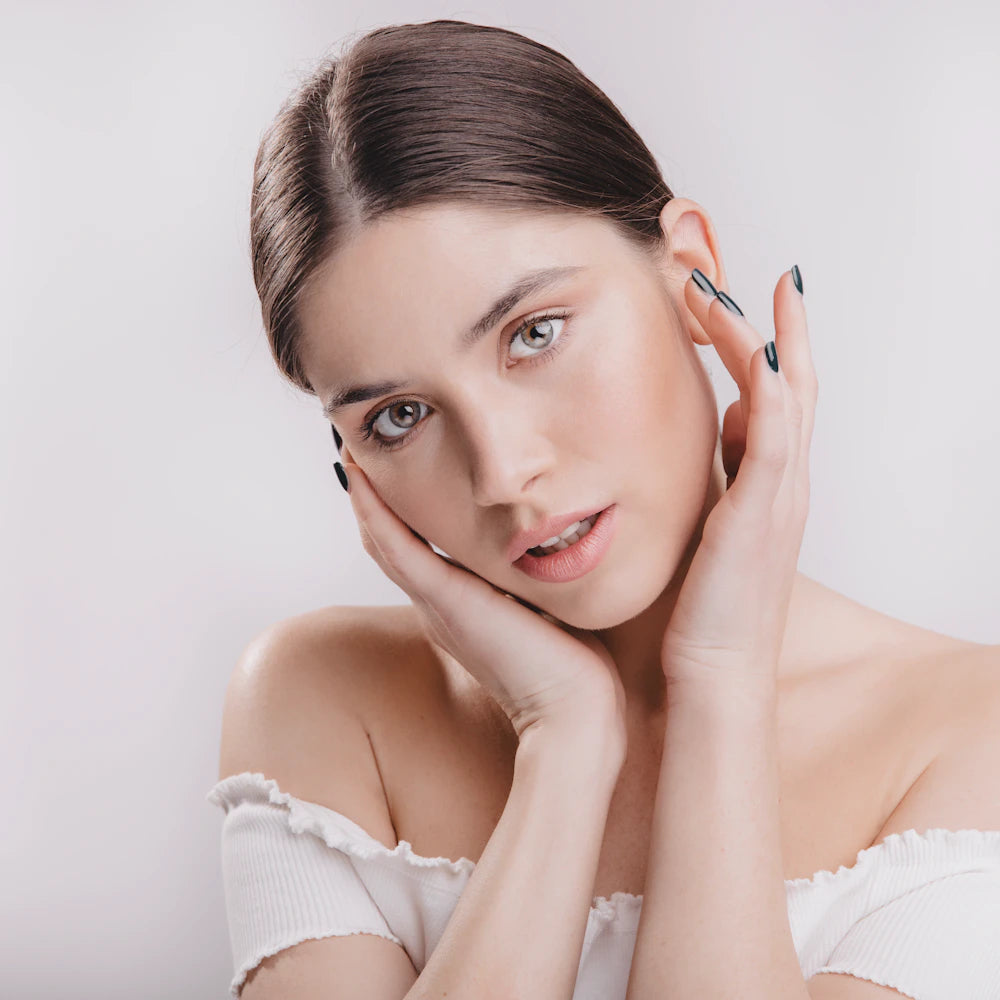 Woman with glowing skin holding her face in her hands
